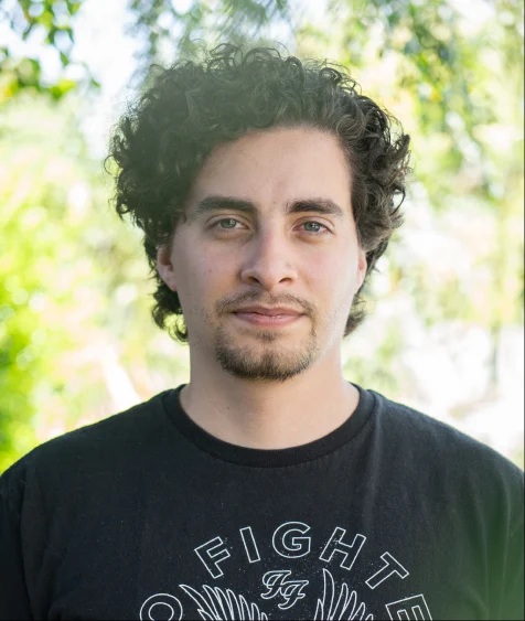 Curly hair man wearing a black shirt.