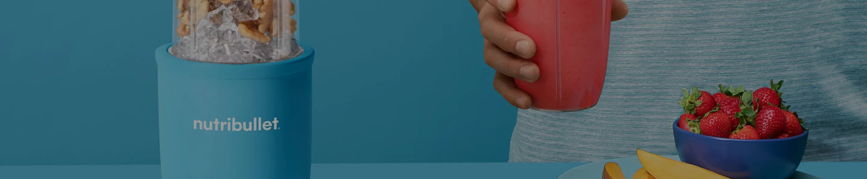 Image of a blue nutribullet, a man holding a pink smoothie and strawberries on a blue background.