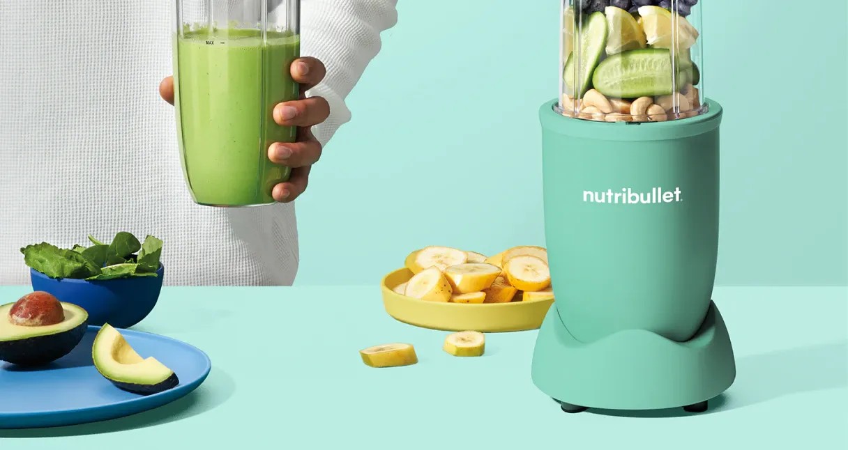 nb-work-desktop.webp nutribullet blender with fruit and nuts on a green background.
