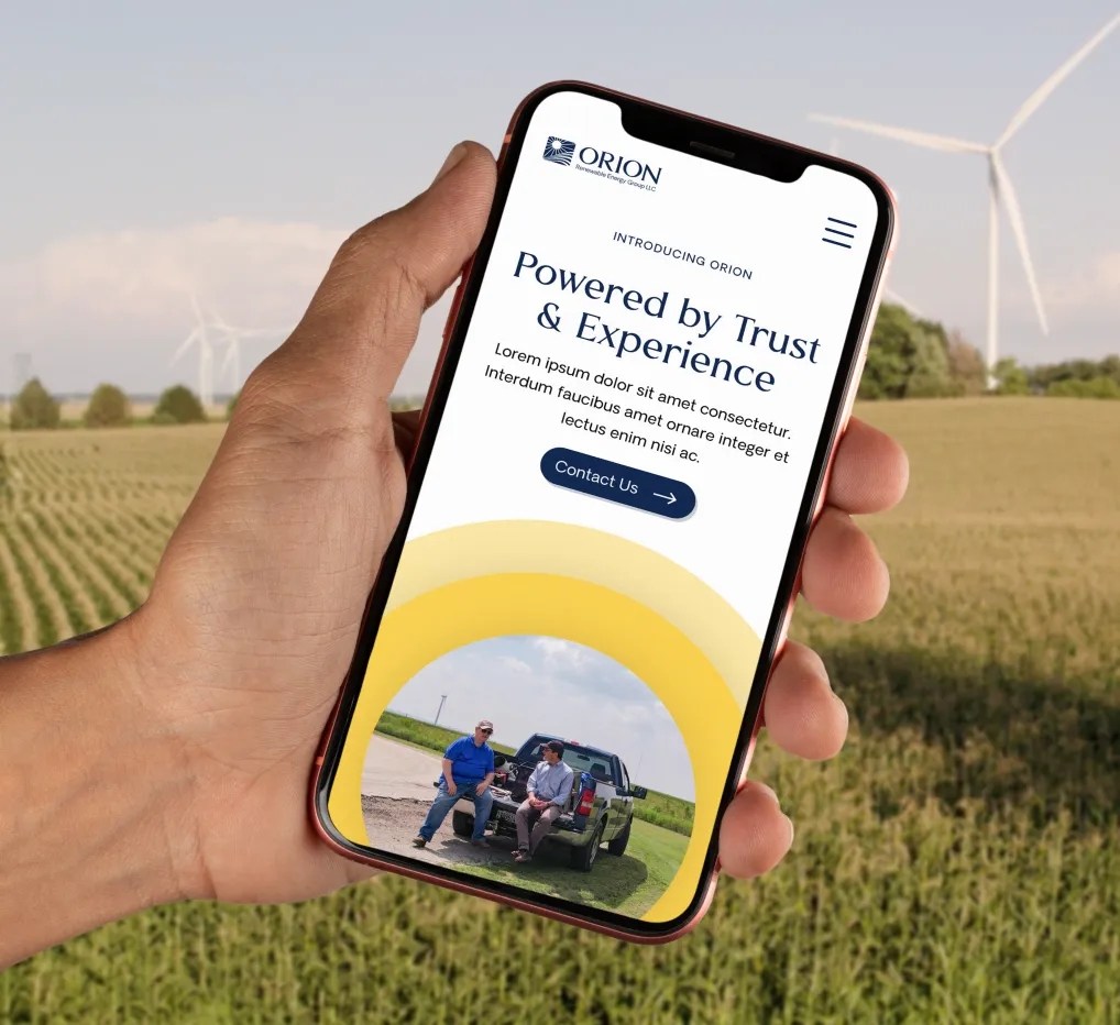orion-stacked-b.webp Hand holding mobile phone displaying Orion's website homepage.